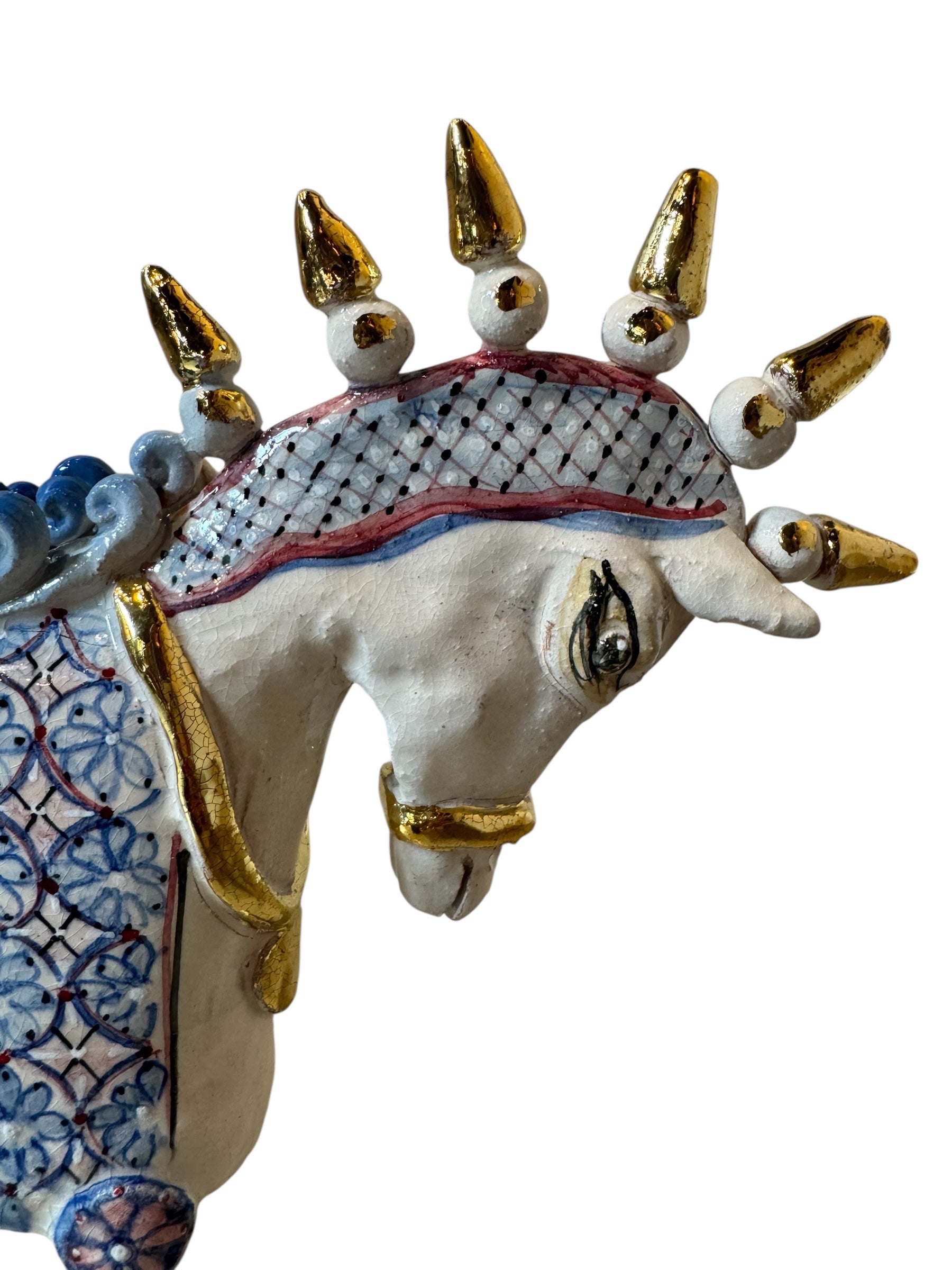 Ceramic horse by Domenico Pinto, featuring a white glazed body, geometric quilting on the saddle, a decorative crown with white and gold accents, and 24Kt gold detailing. The horse stands on four legs and is placed on a white base.