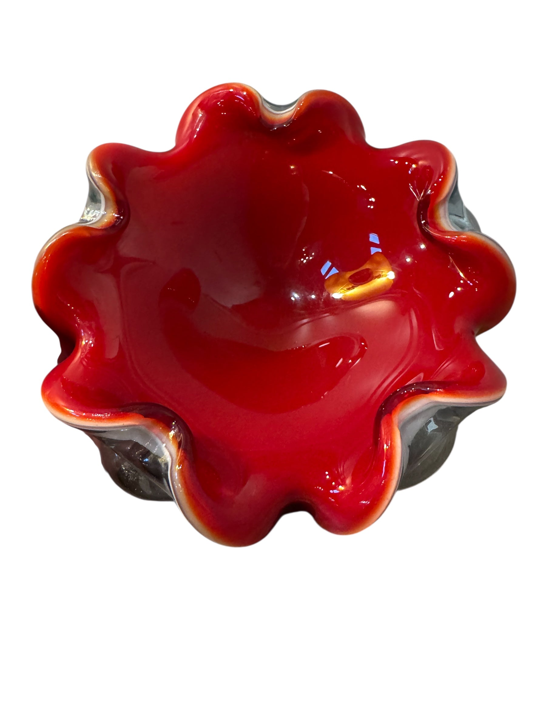 A Murano art glass bowl featuring a vibrant red interior encased in white glass, with a decorative ruffled edge. The piece is handblown, showcasing the Incamiciato technique.