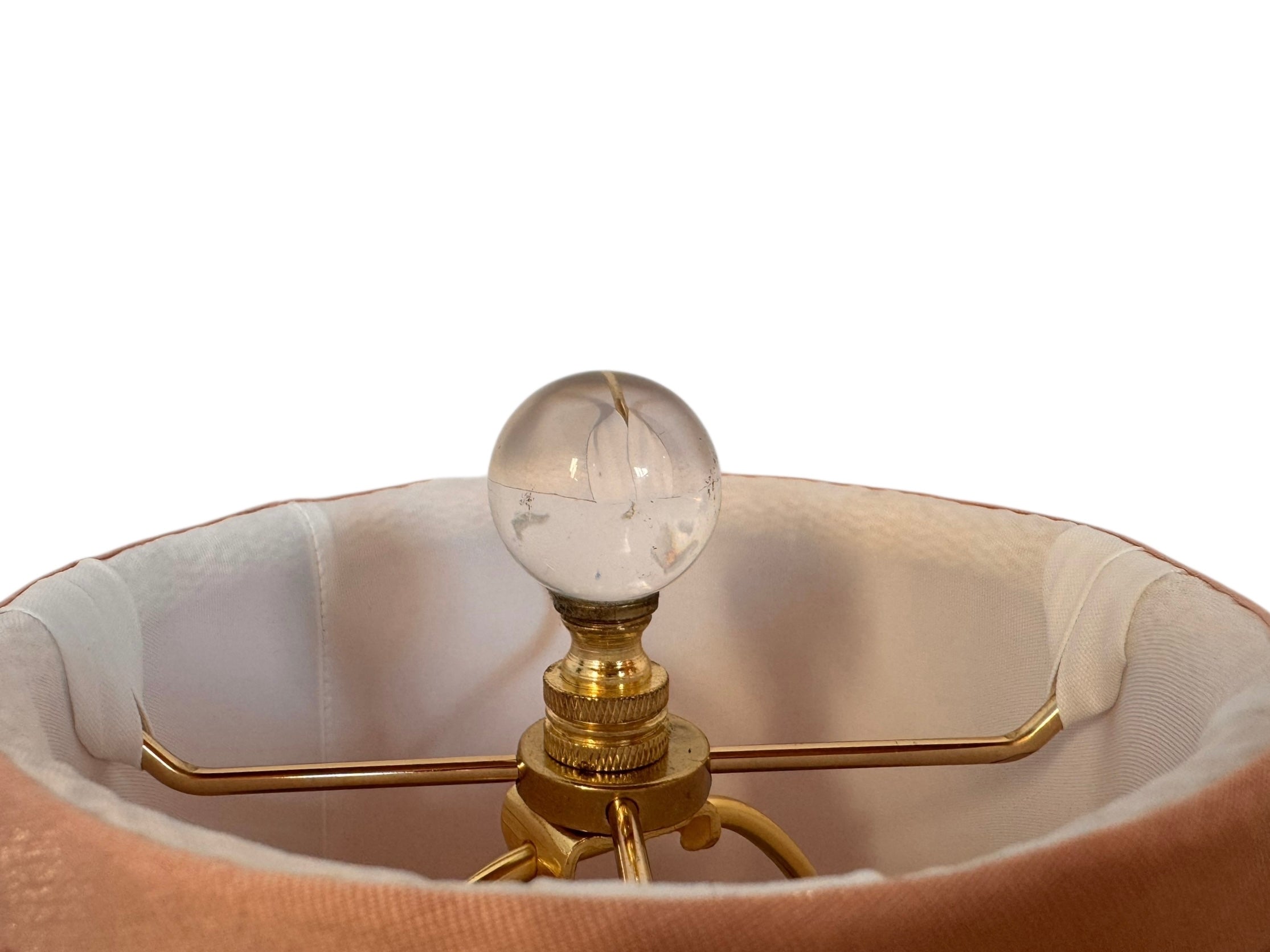 A table lamp featuring a teardrop-shaped, reddish-purple glass base and a conical, pleated, light-pink fabric shade.