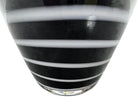 A sleek, hand-blown Polish art glass vase featuring a tall, slender neck that flares into a rounded, bulbous body. The vase is made of opaque black glass decorated with a continuous white spiral ribbon that winds around the entire piece from base to rim. The high-gloss, reflective surface creates sharp highlights, emphasizing its smooth, sculptural silhouette against a plain white background.

