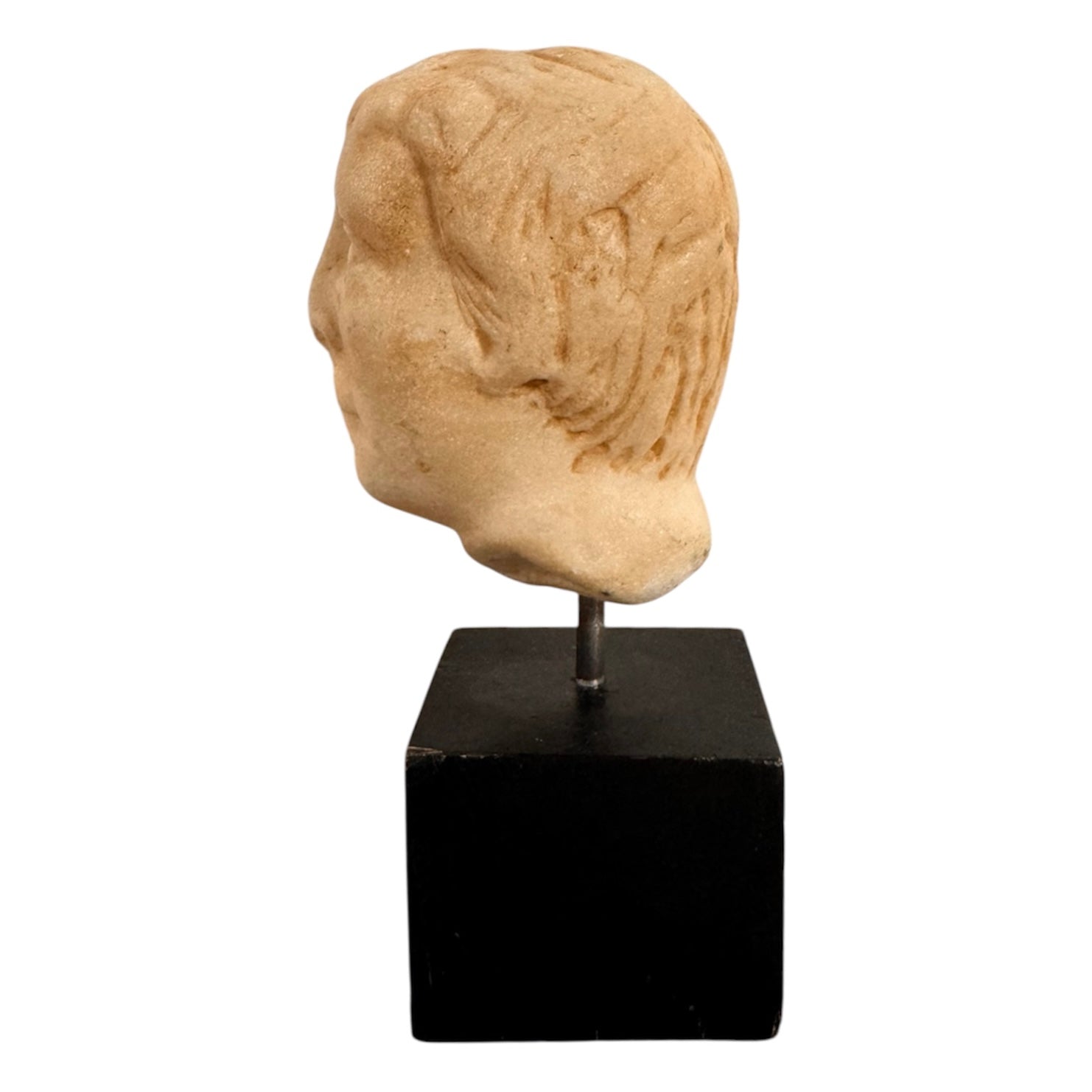 An ancient marble sculpted head of a young man, presented on a modern black presentation stand. The sculpture is rendered in a three-quarter view, angled slightly to the right, showing a classical profile characterized by a strong nose, softly contoured cheekbones, and slightly parted lips that convey a quiet, contemplative expression. The hair is carved in short, stylized strands that frame the forehead and ears, characteristic of ancient Roman or Greek portraiture styles.