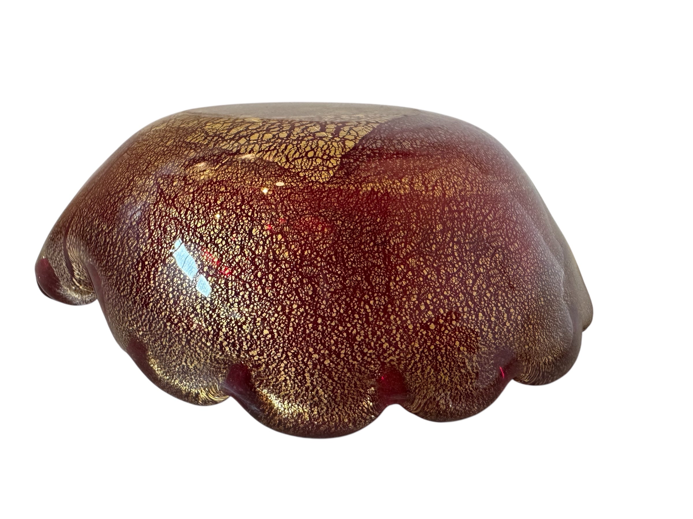 A handcrafted Murano glass bowl with a ruffled edge, deep red color, and gold specks created using the "oro zecchino" technique. The surface has a crackled gold pattern that reflects light, making it a striking decorative piece.