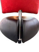 A Leolux Pallone armchair with a large, black, spherical leather seat and a smaller, red, curved leather backrest, supported by short metal legs.