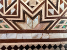 An ornate octagonal Syrian inlaid box, intricately decorated with geometric patterns made from dark wood, iridescent mother-of-pearl, vibrant abalone shell, and pale bone