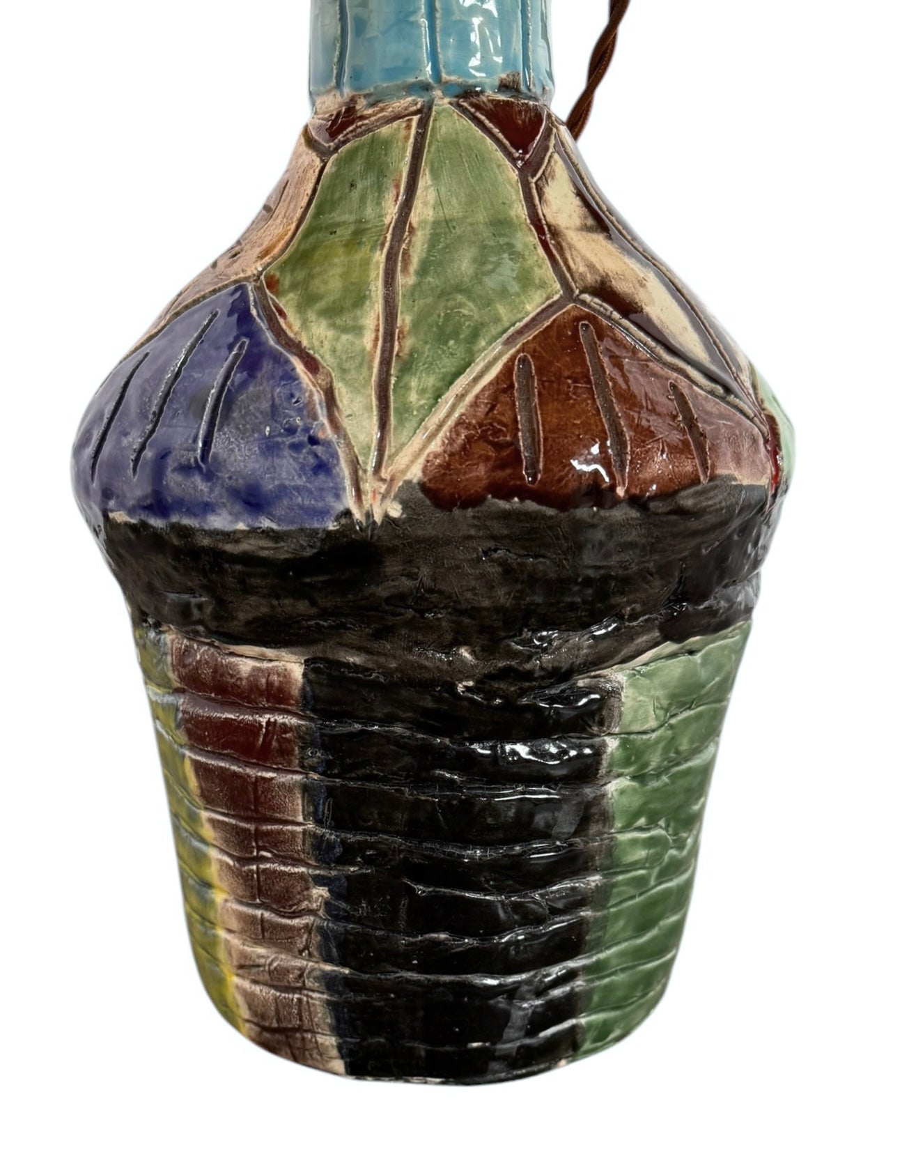 A hand-crafted ceramic table lamp featuring a vibrant, multi-colored base and a sleek black shade. The base is an upcycled artisan vase with a textured, hand-thrown appearance, decorated with geometric panels in shades of mustard yellow, forest green, cobalt blue, and burgundy, separated by thick black outlines. The lamp is topped with a minimalist, black tapered drum shade that provides a sharp contrast to the colorful, eclectic pottery below.
