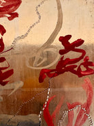 A vertical abstract work on a weathered gold-leaf panel. The upper section features bold, dark red calligraphic symbols resembling distorted kanji or script. Below, delicate, dotted white lines wind through the composition like strings of pearls or constellations. A slender, vertical form in vibrant red stands on the right, while muted, smoky-grey washes of paint ground the bottom of the piece.