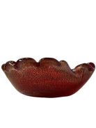 A handcrafted Murano glass bowl with a ruffled edge, deep red color, and gold specks created using the "oro zecchino" technique. The surface has a crackled gold pattern that reflects light, making it a striking decorative piece.