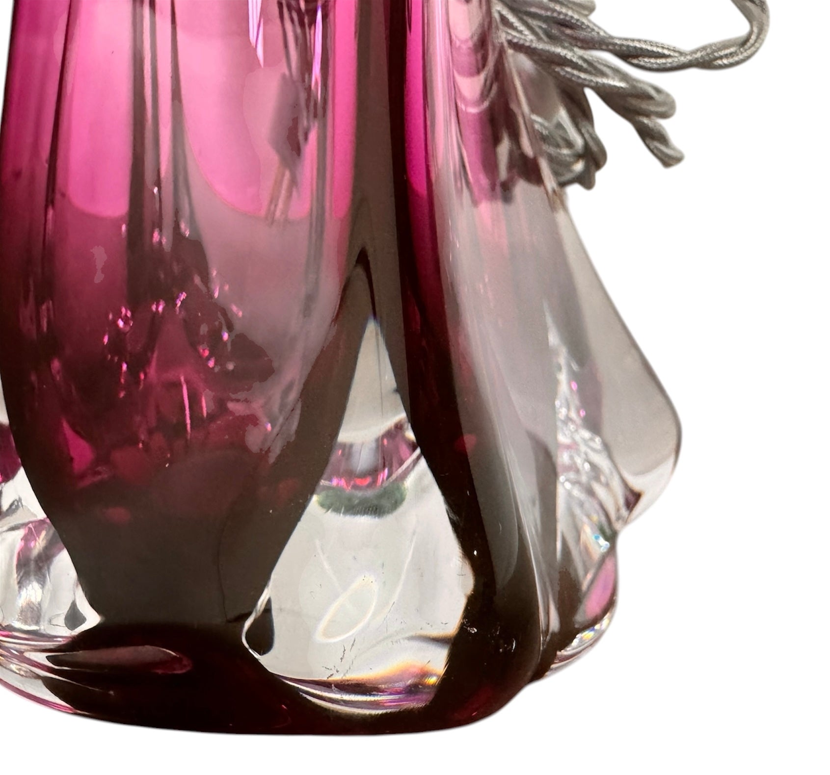 A tall, Mid-Century Modern sculptural table lamp featuring a hand-blown art glass base. The base is crafted in the Sommerso style, with a deep amethyst purple core encased in a thick, clear crystal outer layer that twists upward in an organic, fluid motion. The lamp is topped with a white, knife-pleated empire shade and a clear glass ball finial. The overall design is elegant and slender, emphasizing the contrast between the saturated purple glass and the transparent, light-refracting crystal.