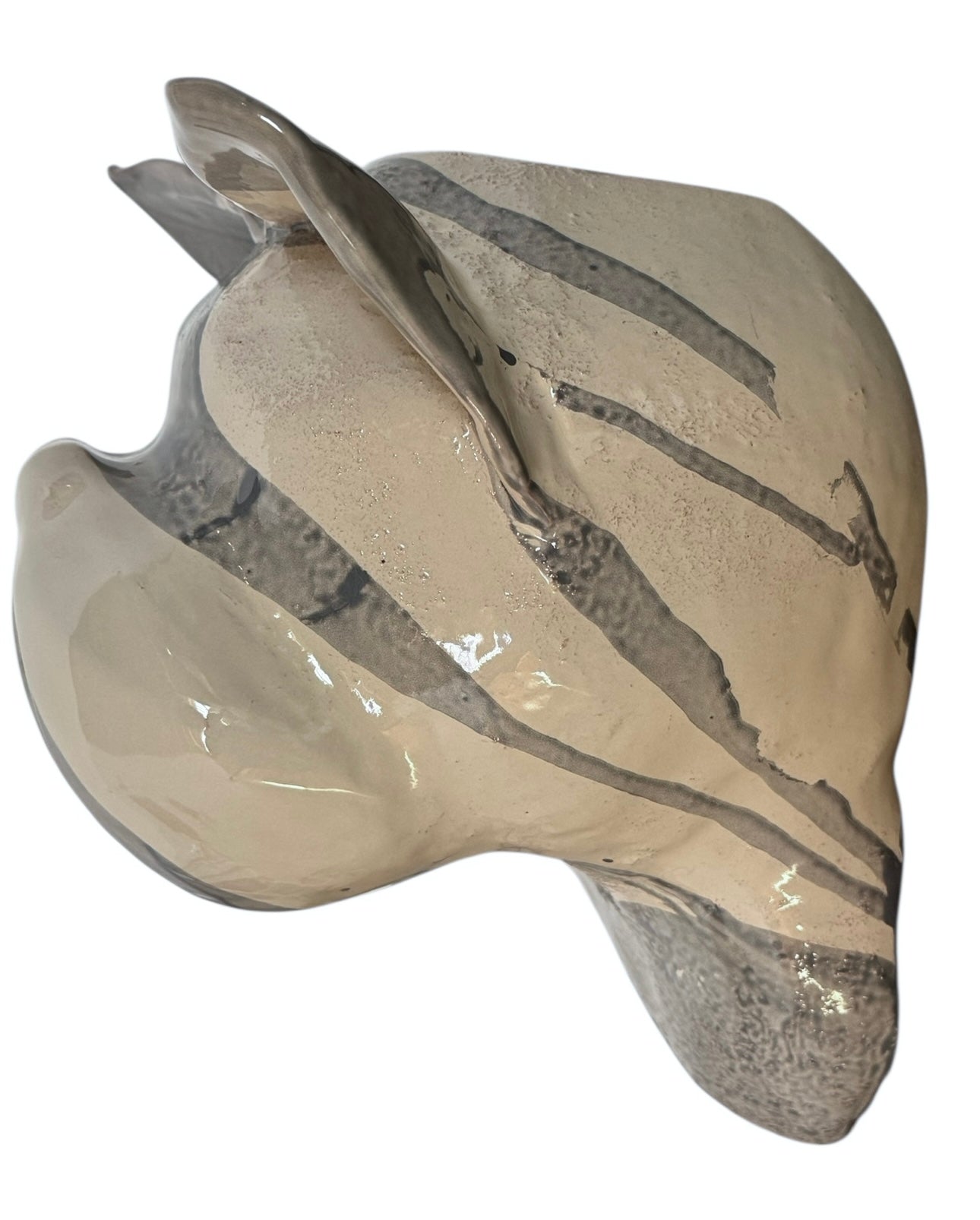 A ceramic sculpture of a bulldog's head by Enza Fasano. The piece features a glossy, glazed finish with a sophisticated color palette of muted greys, creams, and earthy brown tones arranged in bold, abstract striped patterns across the face and ears. The bulldog has characteristic folded ears, a prominent snout, and a soulful, slightly downturned expression. The sculpture is set against a clean, white background, highlighting its smooth texture and reflective surface.