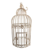 A single, white or cream-colored, decorative wrought iron bird cage with a hinged door and a hanging loop at the top. The cage has a vintage or antique style 