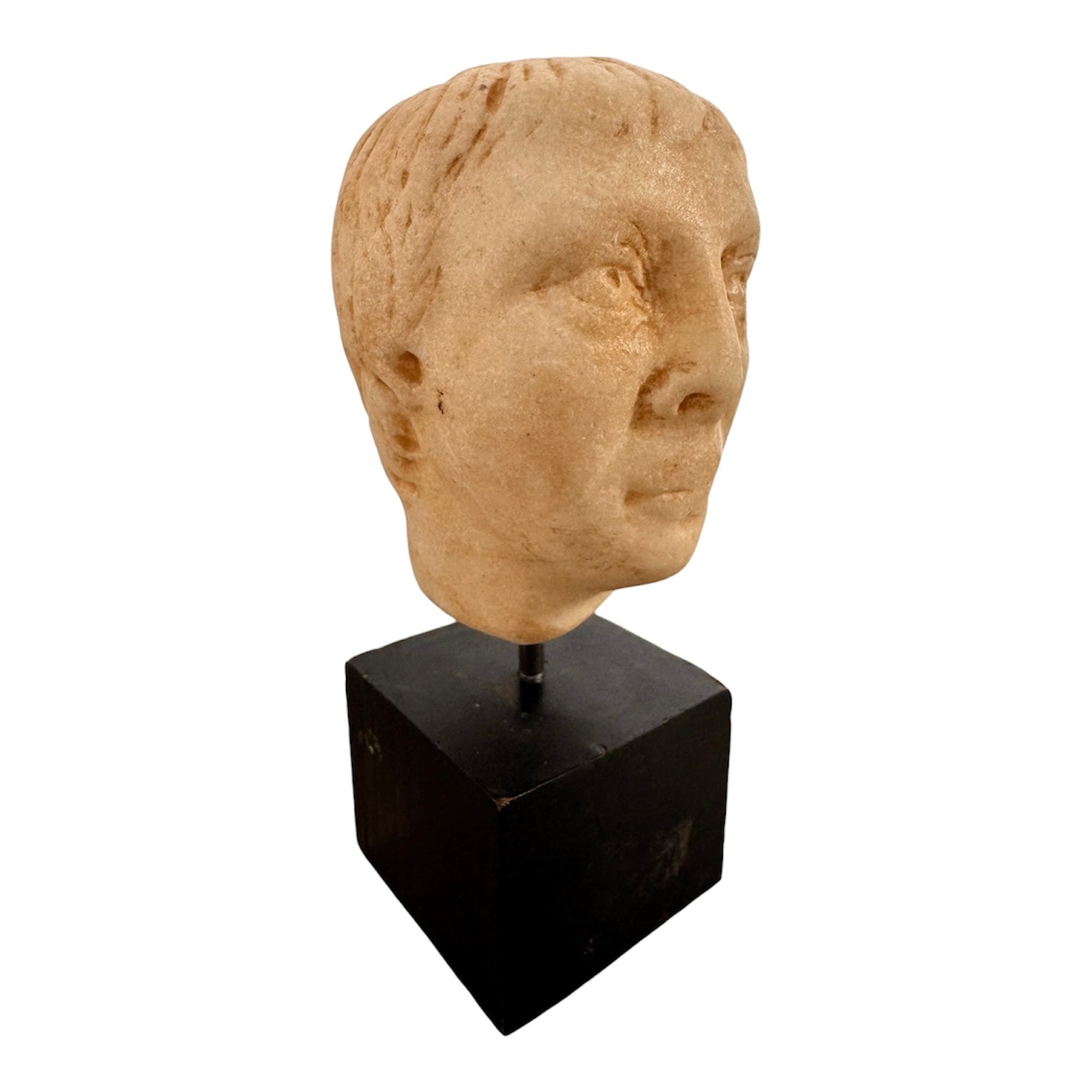 An ancient marble sculpted head of a young man, presented on a modern black presentation stand. The sculpture is rendered in a three-quarter view, angled slightly to the right, showing a classical profile characterized by a strong nose, softly contoured cheekbones, and slightly parted lips that convey a quiet, contemplative expression. The hair is carved in short, stylized strands that frame the forehead and ears, characteristic of ancient Roman or Greek portraiture styles.