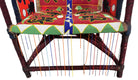 Close-up of a Yoruba beaded armchair, featuring vibrant red, blue, and green beads in a pattern of stylized masks and animals such as lions and zebras