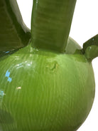 Glossy green ceramic pig sculpture with exaggerated, upward-curving horns and a snout.