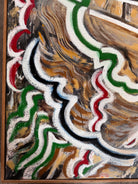 A close-up, angled view of an abstract oil painting titled 'Topography' by Robert Wymer. The painting's edge reveals thick, textured swirls of brown, gold, red, green, and white paint. It is framed in a natural light-brown teak wood frame, with a visible corner joint where two pieces of wood meet