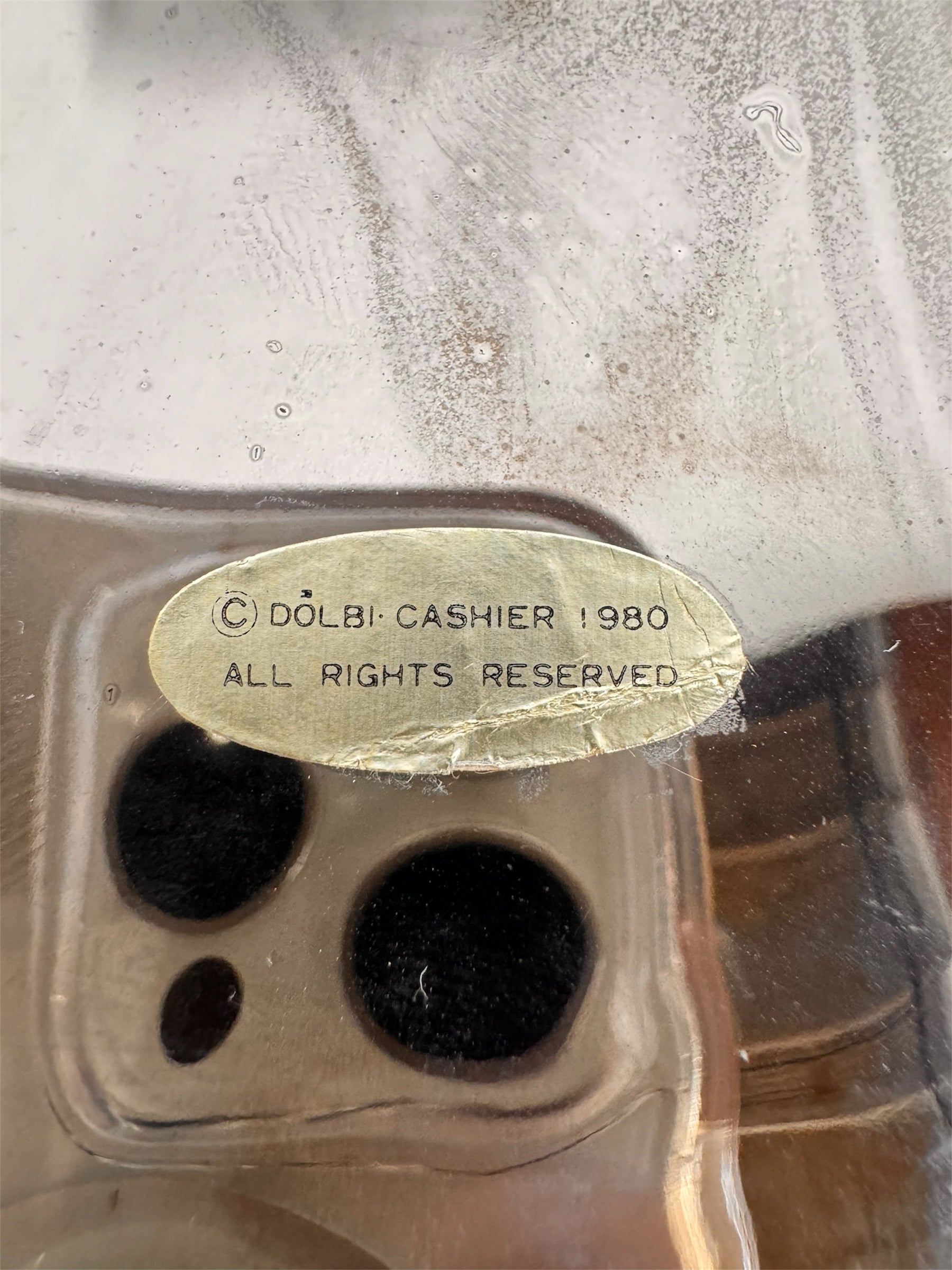 A large, decorative ceramic bowl by Dolbi Cashier in a dramatic Postmodern style. The top half is finished in a polished, piano-black glaze with an organic, wavy "butterfly" rim that dips in the center and rises at the sides. The bottom half is finished in a reflective, metallic silver chrome glaze, featuring bold, geometric-rounded feet and a structured base that appears to "hold" the black vessel. The overall shape is wide and sculptural, reminiscent of 1980s Art Deco Revival.