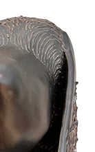 A dark, chocolate-brown ceramic sculpture by Enza Fasano depicting the stylized head of a hunting dog, such as a pointer or hound. The piece features a smooth, elongated snout and large, floppy ears with a textured, feathery finish that contrasts with the sleek crown of the head. The minimalist design emphasizes the dog's elegant profile and long neck.