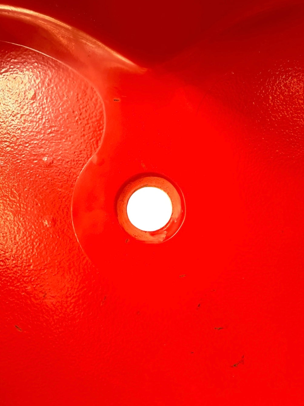 A top-down, straight-on view of a vintage, high-gloss cherry red bathtub. The tub basin is molded into a distinct double-tiered heart shape, with a shallower outer heart cascading into a deeper, smaller inner heart basin centered within a wide rectangular red deck.