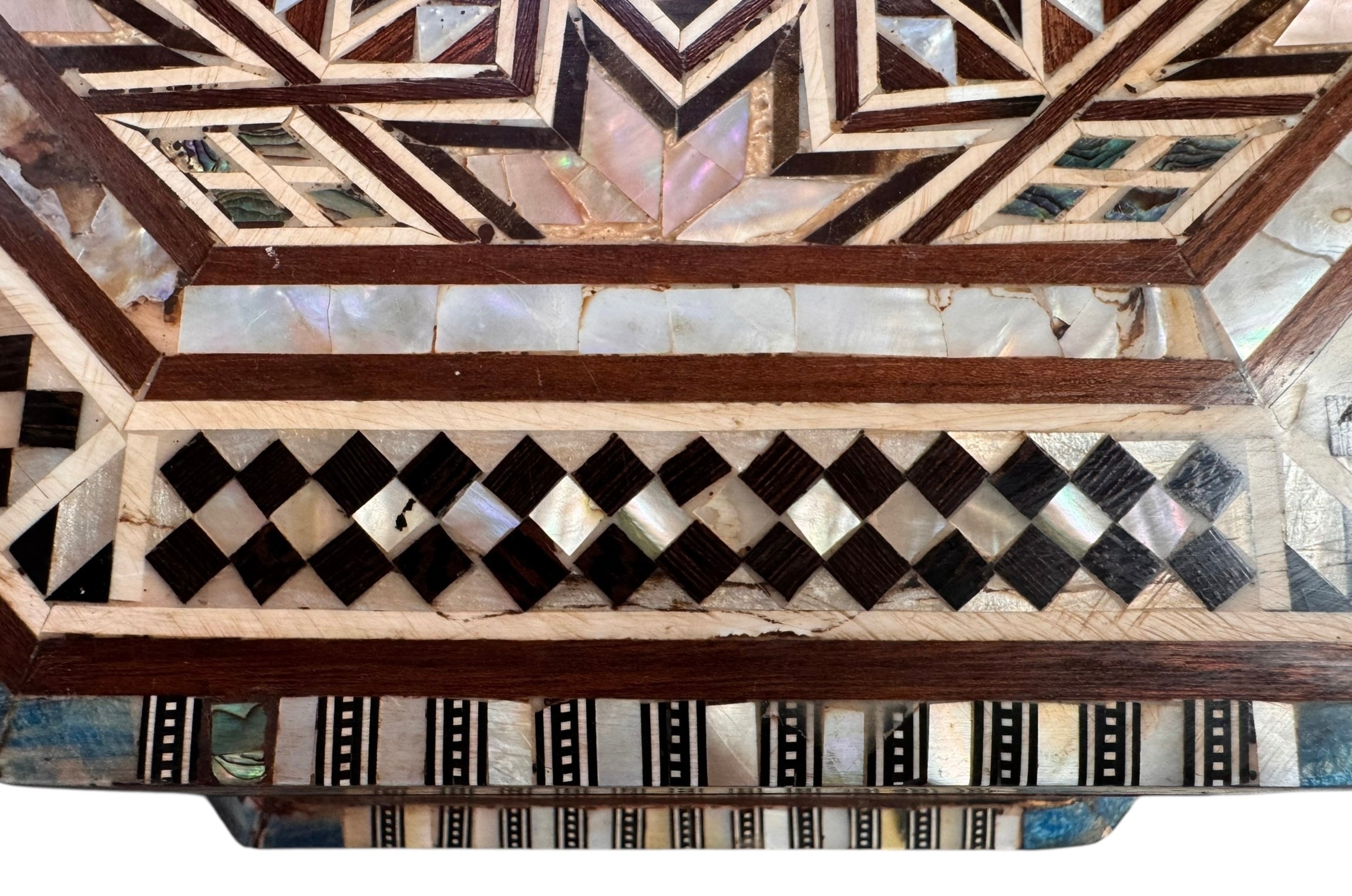 An ornate octagonal Syrian inlaid box, intricately decorated with geometric patterns made from dark wood, iridescent mother-of-pearl, vibrant abalone shell, and pale bone