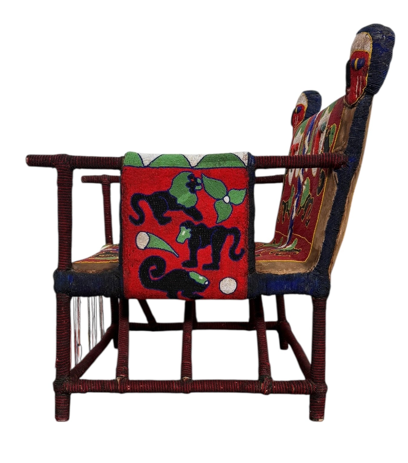 Close-up of a Yoruba beaded armchair, featuring vibrant red, blue, and green beads in a pattern of stylized masks and animals such as lions and zebras