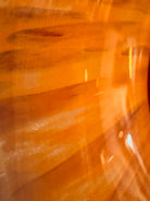 A hand-blown Italian Murano glass vase featuring a wide, bulbous body and a short, flared rim. The glass is a vibrant, translucent amber-orange base decorated with an organic "macchia" or spotted pattern of deep ruby red blotches. The red spots are elongated and vertical near the neck, becoming larger and more rounded toward the base. The surface has a high-gloss, reflective finish, showcasing mid-century modern craftsmanship.
