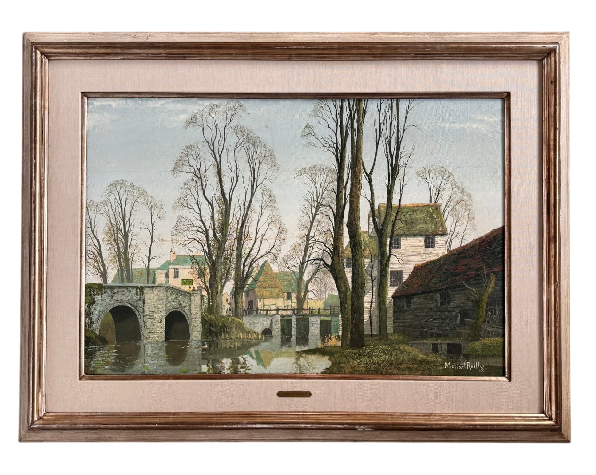 A naturalistic landscape oil painting by Michael Reilly titled "Mill Pond with Bridge" depicts a small town scene with a stone bridge over a mill pond, several buildings, and numerous bare trees under a grey sky