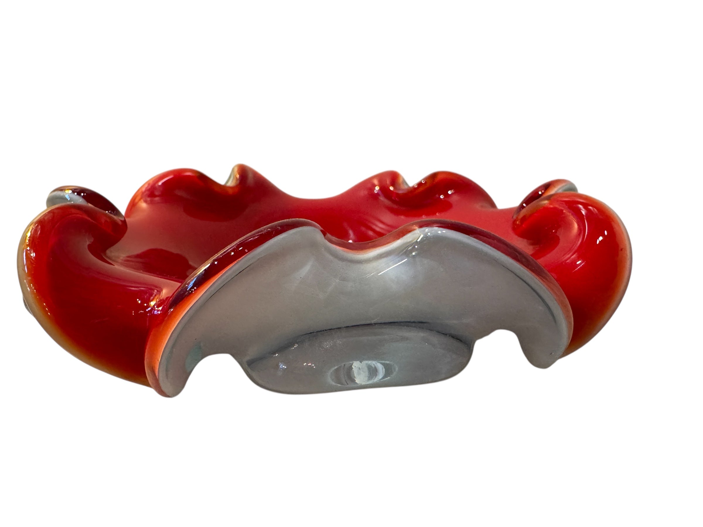 A Murano art glass bowl featuring a vibrant red interior encased in white glass, with a decorative ruffled edge. The piece is handblown, showcasing the Incamiciato technique.