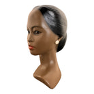 a vintage ceramic bust featuring a woman with brown skin, dark eyes, and orange lips. Her black hair is sleek and parted on the side, pulled back into a low style. She wears a small, round white earring in her right ear lobe. The bust includes her head, neck, and the upper part of her shoulders