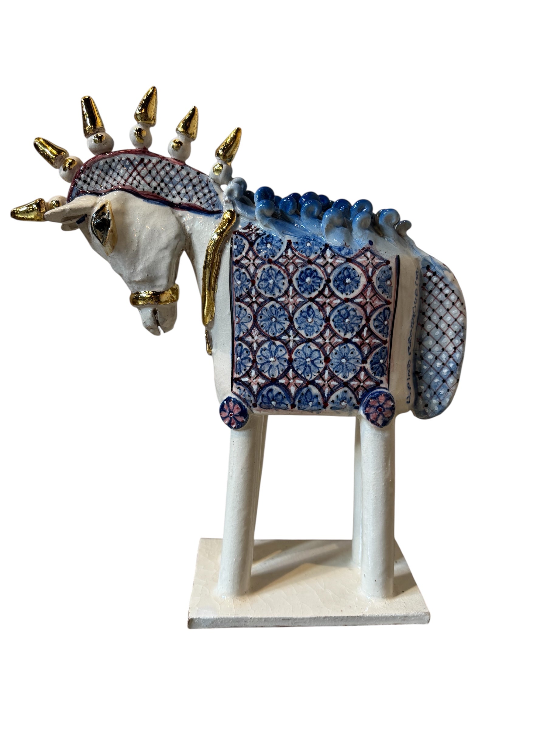 Ceramic horse by Domenico Pinto, featuring a white glazed body, geometric quilting on the saddle, a decorative crown with white and gold accents, and 24Kt gold detailing. The horse stands on four legs and is placed on a white base.
