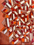 Abstract artwork with geometric shapes in red, orange, and white on a wooden background