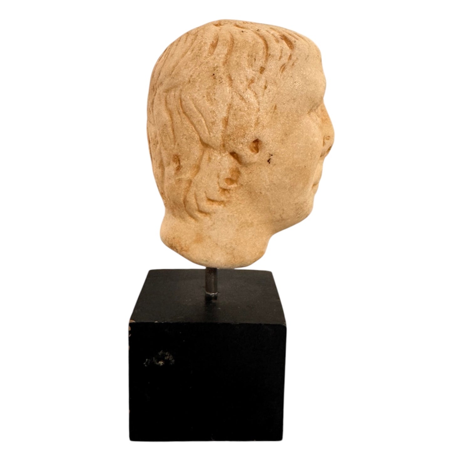 An ancient marble sculpted head of a young man, presented on a modern black presentation stand. The sculpture is rendered in a three-quarter view, angled slightly to the right, showing a classical profile characterized by a strong nose, softly contoured cheekbones, and slightly parted lips that convey a quiet, contemplative expression. The hair is carved in short, stylized strands that frame the forehead and ears, characteristic of ancient Roman or Greek portraiture styles.