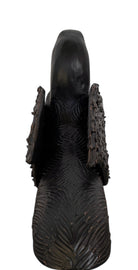 A dark, chocolate-brown ceramic sculpture by Enza Fasano depicting the stylized head of a hunting dog, such as a pointer or hound. The piece features a smooth, elongated snout and large, floppy ears with a textured, feathery finish that contrasts with the sleek crown of the head. The minimalist design emphasizes the dog's elegant profile and long neck.
