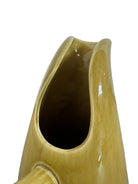 A chartreuse (yellow-green) ceramic pitcher designed by Russel Wright, featuring a teardrop shape, an elongated spout, and a curved handle