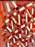 Mosaic artwork with geometric shapes in red, orange, and white on a wooden background