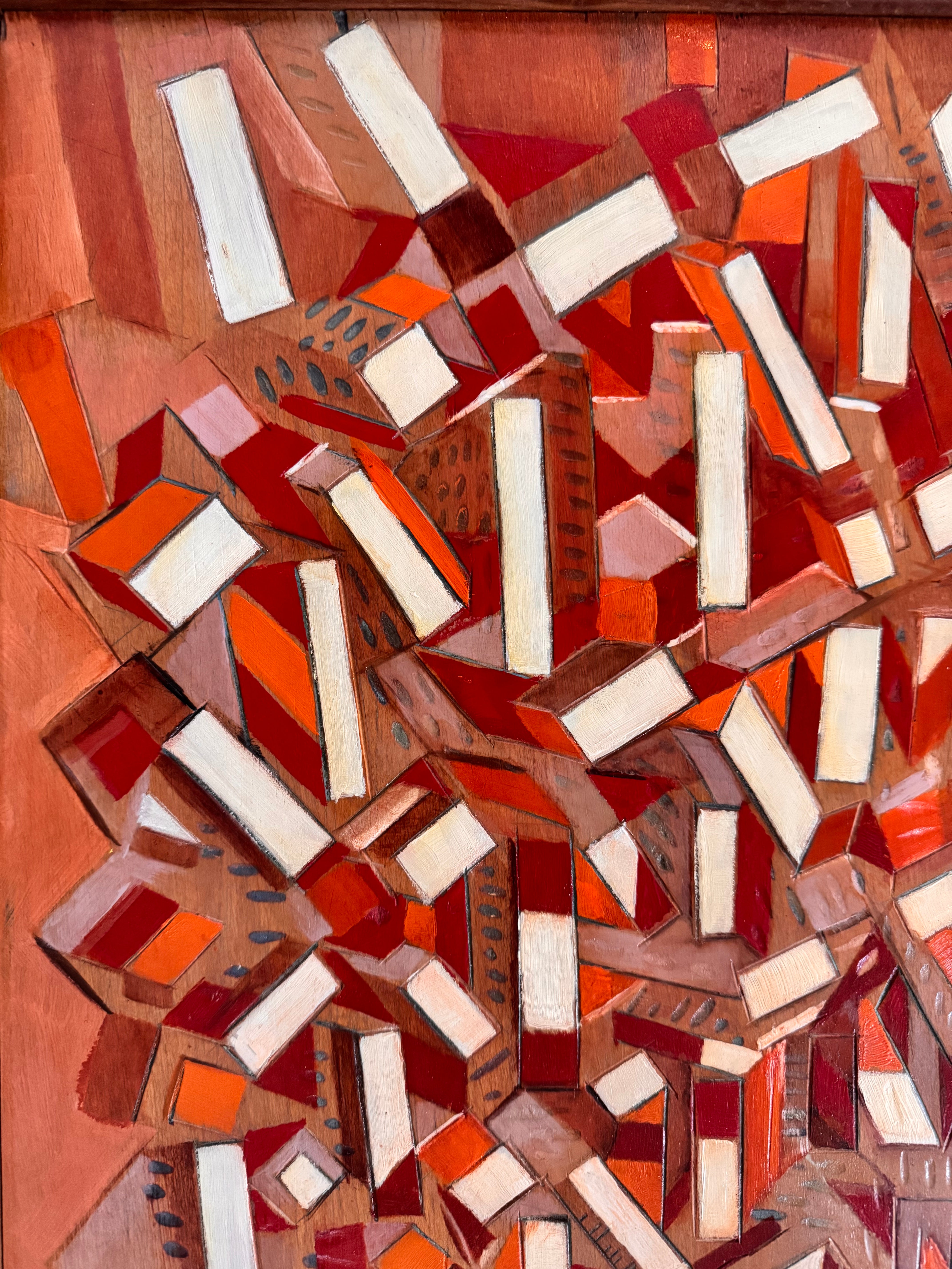 Mosaic artwork with geometric shapes in red, orange, and white on a wooden background
