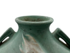 A squat, rounded vintage Roseville pottery vase in a light teal-blue matte glaze. The vase features two small, angular geometric handles on its shoulders and a flared rim. Embossed on the front is a cluster of textured, green and pale-yellow thornapple blossoms tucked against sharp, serrated green leaves. The surface shows a subtle, fine network of age-related crazing lines throughout the glaze.