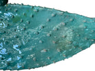 A green and red, glazed ceramic platter in the shape of a prickly pear cactus pad with attached prickly pear fruit. The surface has raised dots representing spines. 