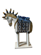Ceramic horse by Domenico Pinto, featuring a white glazed body, geometric quilting on the saddle, a decorative crown with black and gold accents, and 24Kt gold detailing. The horse stands on four legs and is placed on a white base.
