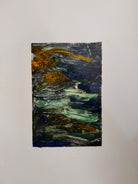 A vertical rectangular artwork, "Embers," by Jill London (2003), framed in a wide, textured gold frame. The piece features a small, abstract expressionist print at the center, rendered in dark, painterly strokes of deep blues, browns, yellows, and white, resembling moving water or smoke. Below the print, on the cream mat, the artist's signature, title, and date are hand-written in pencil. The paper has a delicate, textured deckled edge.