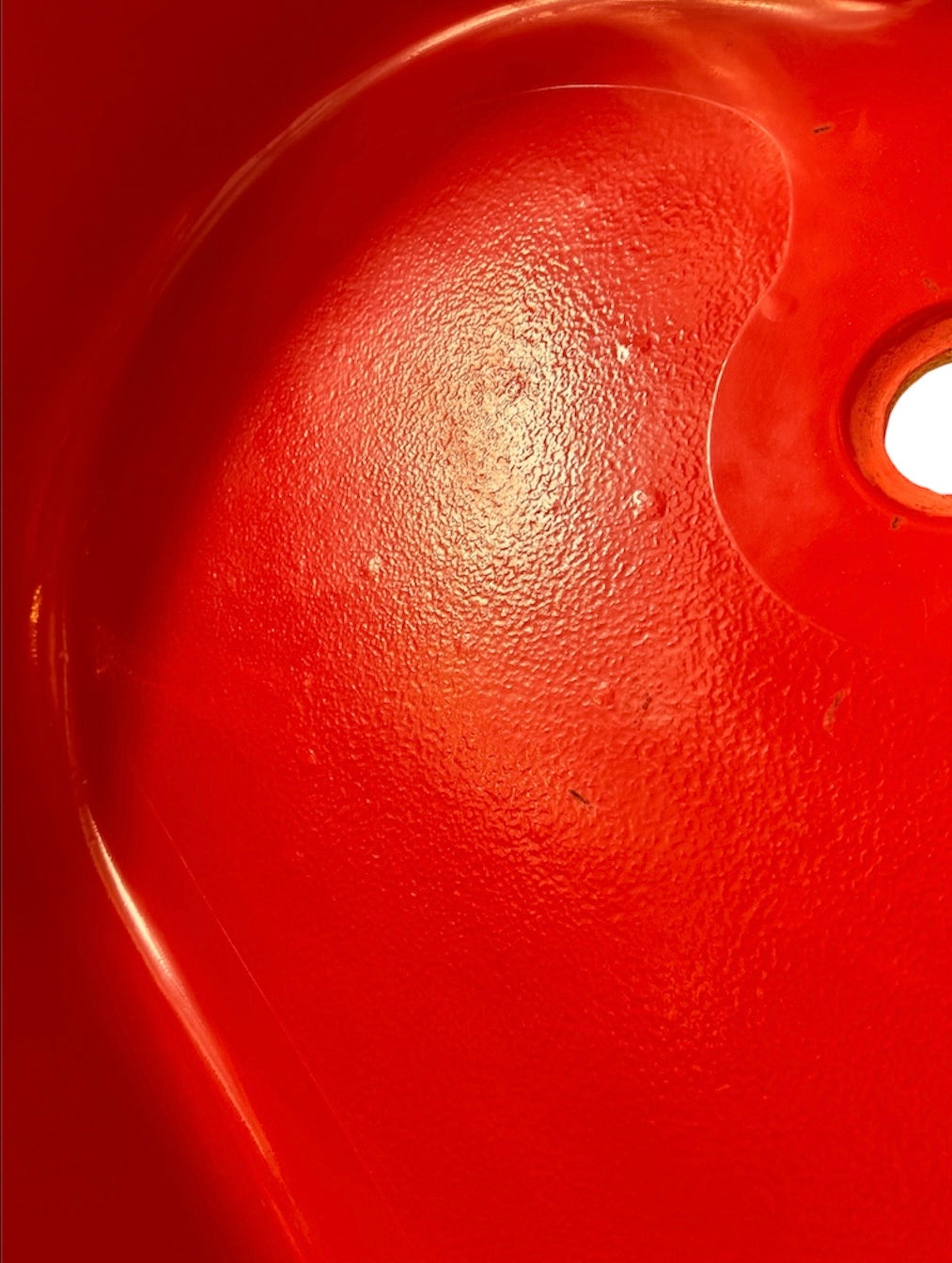 A top-down, straight-on view of a vintage, high-gloss cherry red bathtub. The tub basin is molded into a distinct double-tiered heart shape, with a shallower outer heart cascading into a deeper, smaller inner heart basin centered within a wide rectangular red deck.