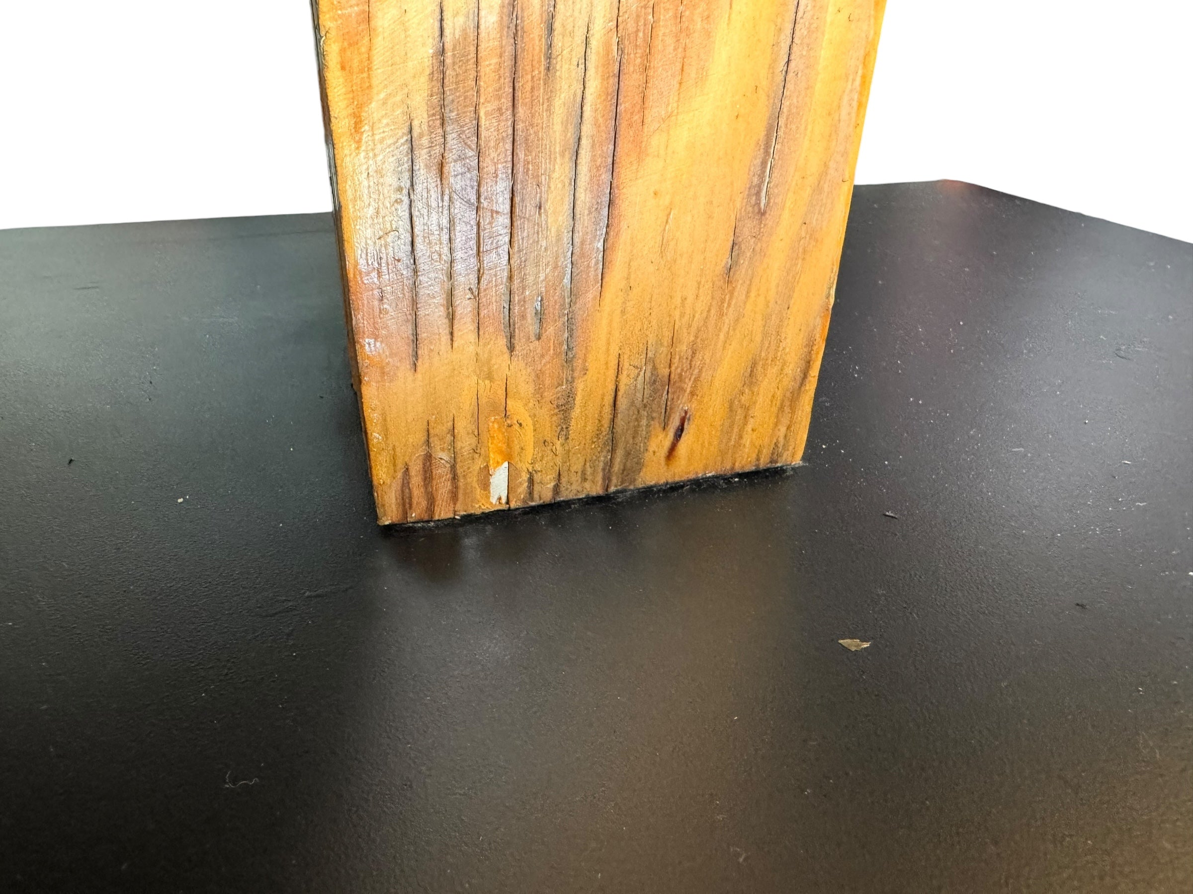 A wooden sculpture featuring a dark square base, a vertical trunk that branches into two angled supports, and a turned wooden sphere resting on the higher support.