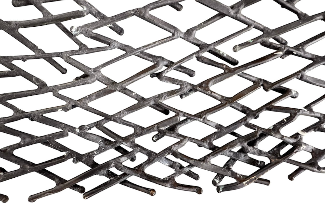 A round metal wall sculpture by Michael Aram, viewed from the front against a stark white background. The piece is composed of a dense, intricate lattice of fine, dark metal wire or twigs woven together to create a textured, web-like pattern. The structure curves inward like a funnel or a vortex, sloping down toward a clean, circular opening in the exact center, creating a strong sense of depth and dimensionality.