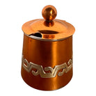 The set includes a large, rectangular, hammered copper tray with geometric openwork handles. Resting on the tray is a tall, slightly tapered copper coffee pot with a wooden handle, a matching smaller creamer pitcher with a similar wooden handle, a lidded sugar bowl, and a tiny matching metal cup or jigger. To the right off the tray sits a large, spherical copper water pitcher or jug with a wide mouth and ice lip.