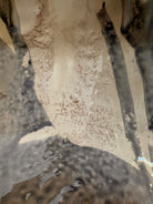 A ceramic sculpture of a bulldog's head by Enza Fasano. The piece features a glossy, glazed finish with a sophisticated color palette of muted greys, creams, and earthy brown tones arranged in bold, abstract striped patterns across the face and ears. The bulldog has characteristic folded ears, a prominent snout, and a soulful, slightly downturned expression. The sculpture is set against a clean, white background, highlighting its smooth texture and reflective surface.