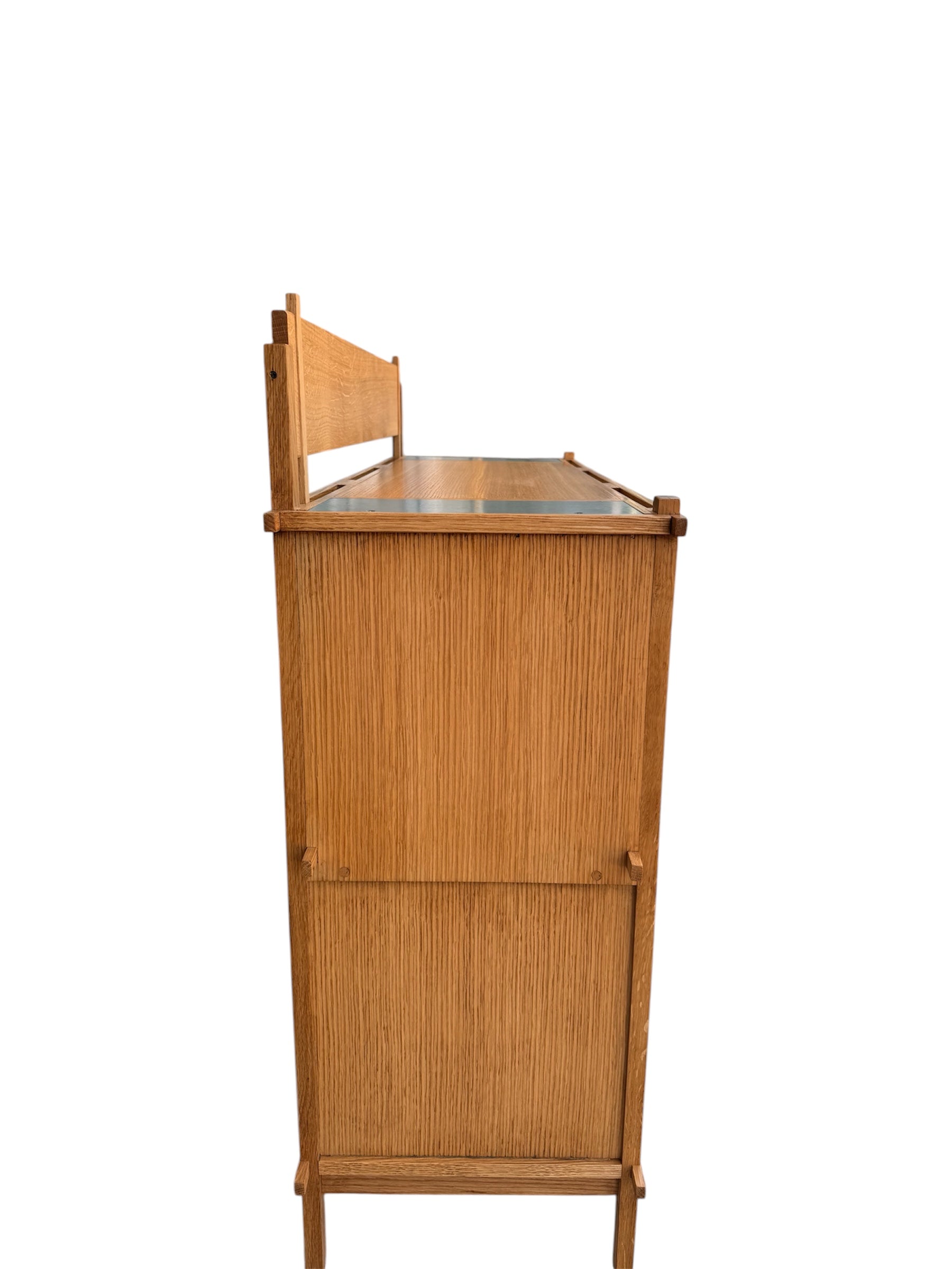 A three-tiered wooden shelving unit featuring a mix of light oak and teal-colored panels. The piece has an open, structural design with visible joinery, vertical supports that extend past the top shelf, and a horizontal backrest at the top. The middle and bottom shelves feature slatted wood center sections flanked by solid teal panels, while the top surface is primarily solid wood with teal accents at the edges.