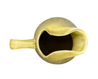 A chartreuse (yellow-green) ceramic pitcher designed by Russel Wright, featuring a teardrop shape, an elongated spout, and a curved handle