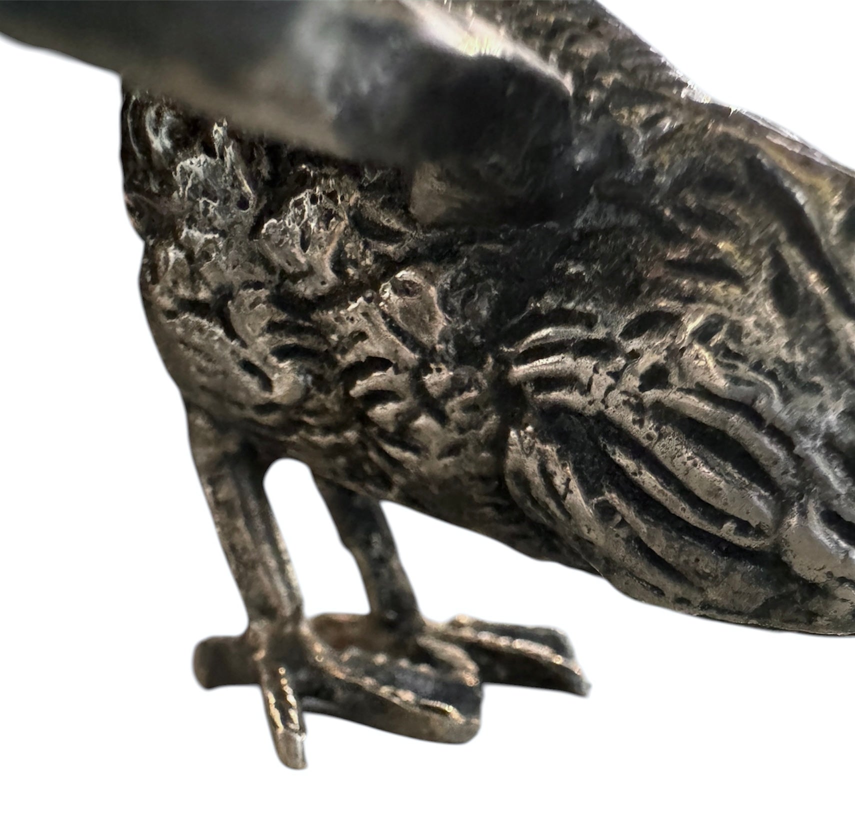 A pair of vintage, silver-plated brass fighting rooster figurines positioned in a confrontational stance against a white background. The rooster on the left is crouched low with its head down and tail feathers fanned high, while the rooster on the right stands more upright with its wings slightly flared. Both feature intricate feather detailing, a metallic patina showing hints of brass through the silver, and small, bright red glass eyes.