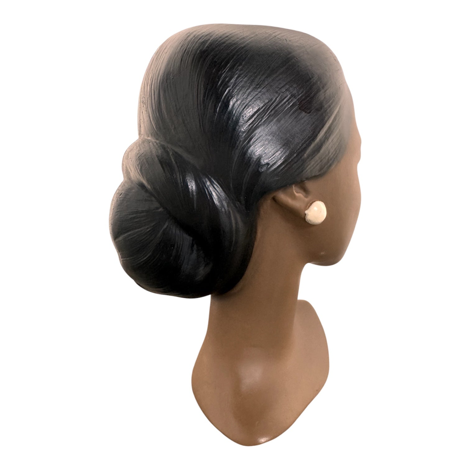 a vintage ceramic bust featuring a woman with brown skin, dark eyes, and orange lips. Her black hair is sleek and parted on the side, pulled back into a low style. She wears a small, round white earring in her right ear lobe. The bust includes her head, neck, and the upper part of her shoulders