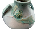 A squat, rounded vintage Roseville pottery vase in a light teal-blue matte glaze. The vase features two small, angular geometric handles on its shoulders and a flared rim. Embossed on the front is a cluster of textured, green and pale-yellow thornapple blossoms tucked against sharp, serrated green leaves. The surface shows a subtle, fine network of age-related crazing lines throughout the glaze.