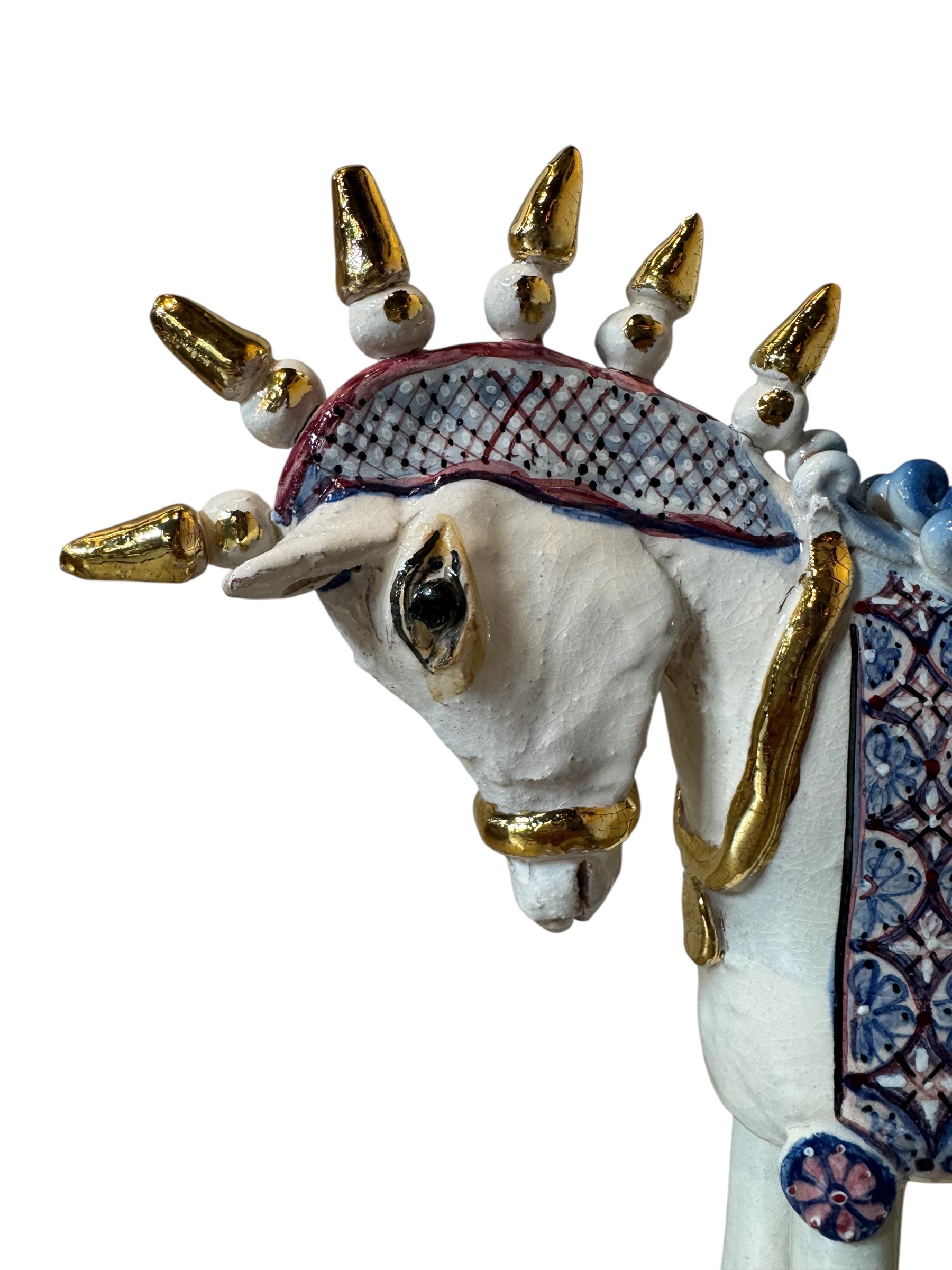 Ceramic horse by Domenico Pinto, featuring a white glazed body, geometric quilting on the saddle, a decorative crown with white and gold accents, and 24Kt gold detailing. The horse stands on four legs and is placed on a white base.