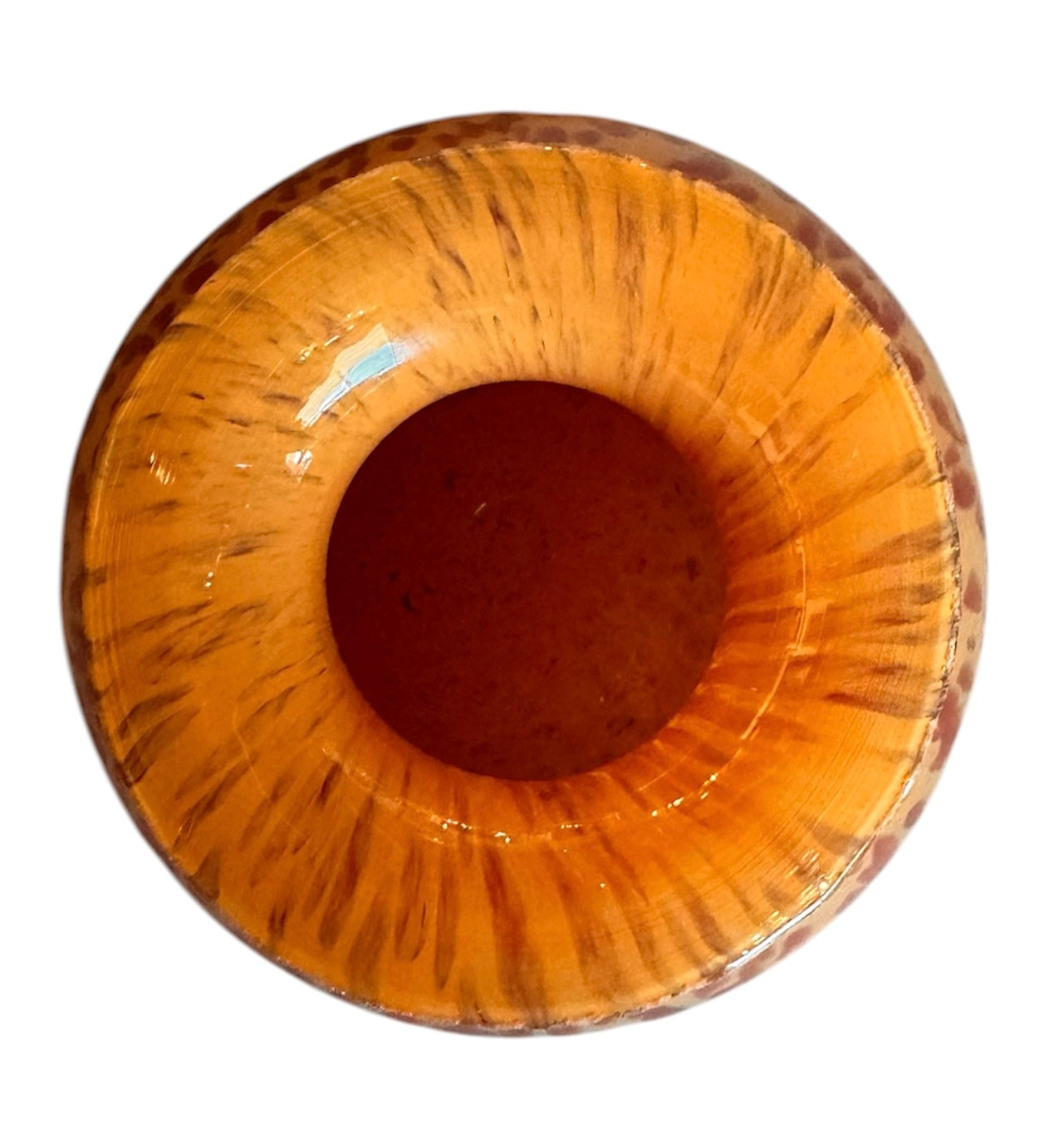 A hand-blown Italian Murano glass vase featuring a wide, bulbous body and a short, flared rim. The glass is a vibrant, translucent amber-orange base decorated with an organic "macchia" or spotted pattern of deep ruby red blotches. The red spots are elongated and vertical near the neck, becoming larger and more rounded toward the base. The surface has a high-gloss, reflective finish, showcasing mid-century modern craftsmanship.

